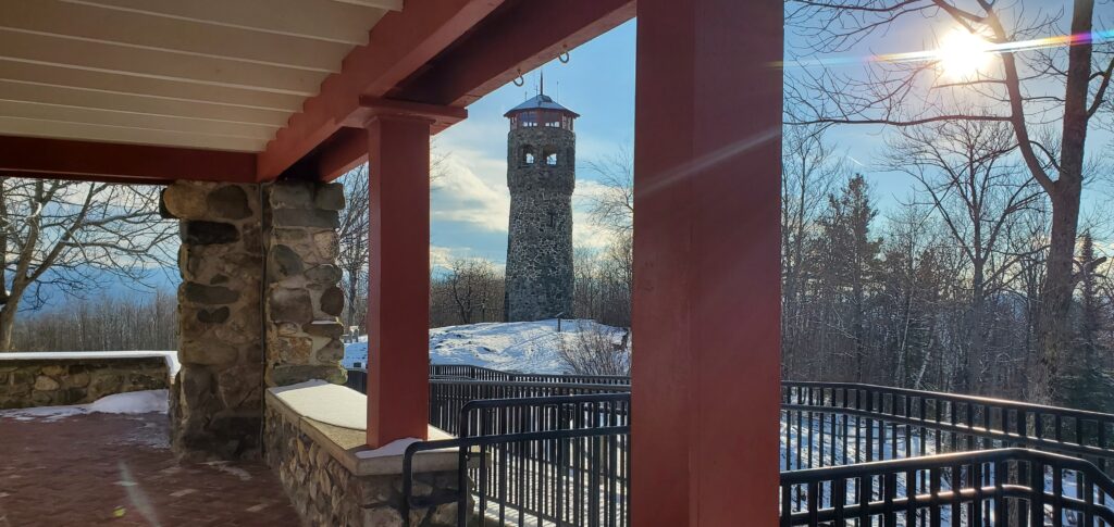 A view from the caretaker's cottage of the Mount Prospect Fire Tower and setting sun.