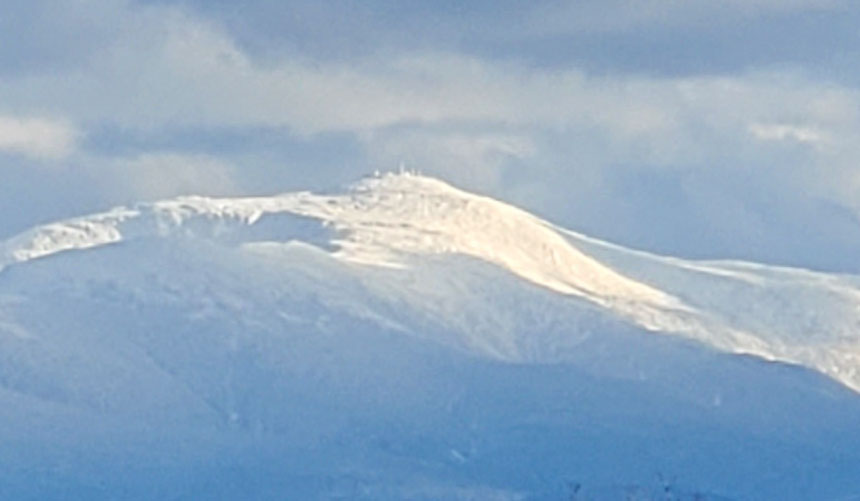 zoomed in image of snow-covered Mount Washington with barely visible observatory